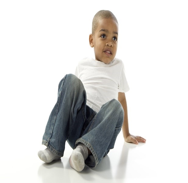 Little boy sitting on the floor in jeans and a white tshirt. No visible injuries.